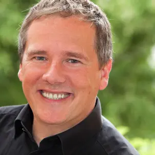 Porträtfoto Dirk Schäuble im schwarzen Hemd lächelt in die Kamera.