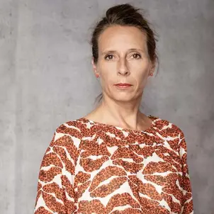 Porträtfoto Ricarda Lang trägt ein gemustertes Kleid und blickt streng in die Kamera.