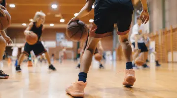 Blick auf eine Gruppe von Kindern die in einer Turnhalle Basketball spielen