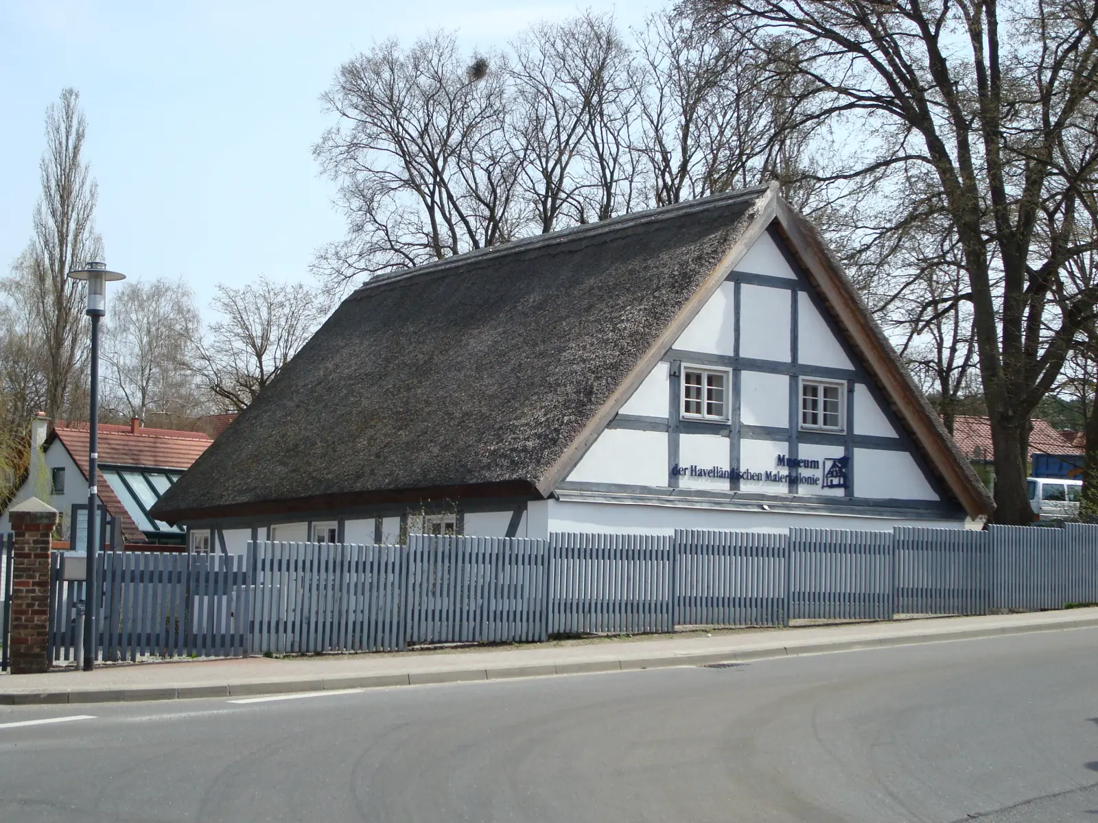 Das Museumsgebäude mit Reetdach hinter einem Holzzaun