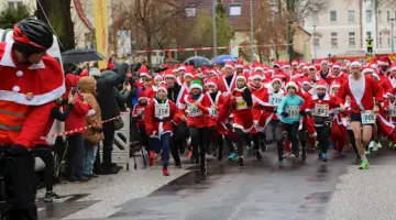 Die Teilnehmer rennen in ihren Nikolausoutfits und ein Fahrradfahrer fährt die Strecke voraus