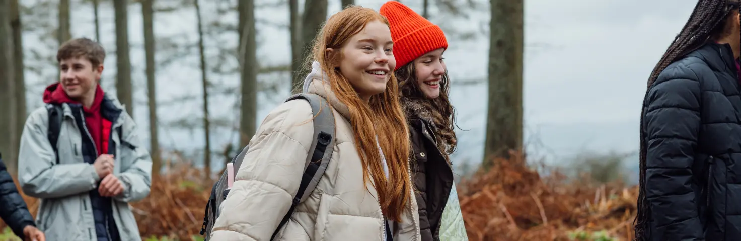 Schülern wandern lachend durch einen Wald