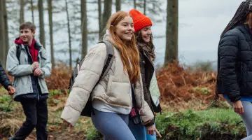 Schülern wandern lachend durch einen Wald