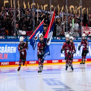 Fünf Nachwuchs-Spieler der Eisbären Juniors skaten im April 2024 mit wehenden Fahnen über die Eisfläche.