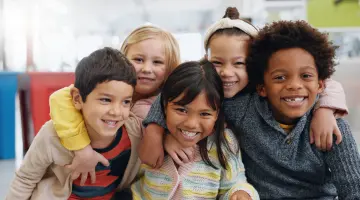 Eine Gruppe Kinder umarmt sich und lacht dabei