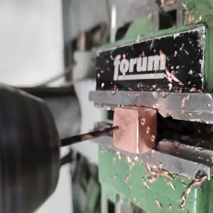 In einen kupferfarbenen Metall-Würfel wird ein Loch gefräst