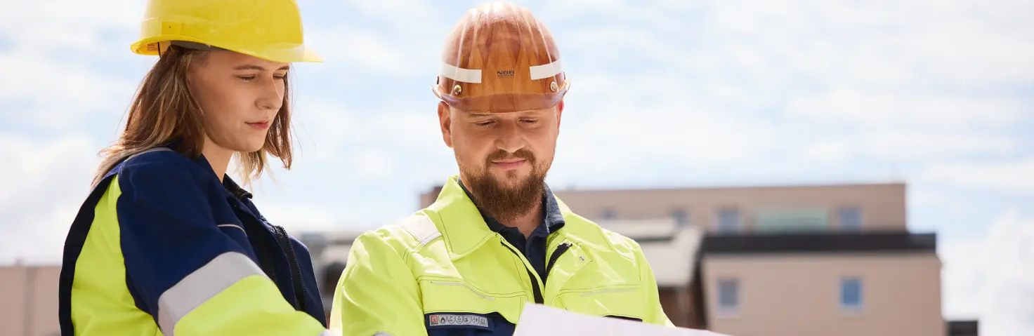 Mitarbeitende der NBB-Netzgesellschaft in gelber Schutzweste und mit Sicherheitshelm halten einen Plan.