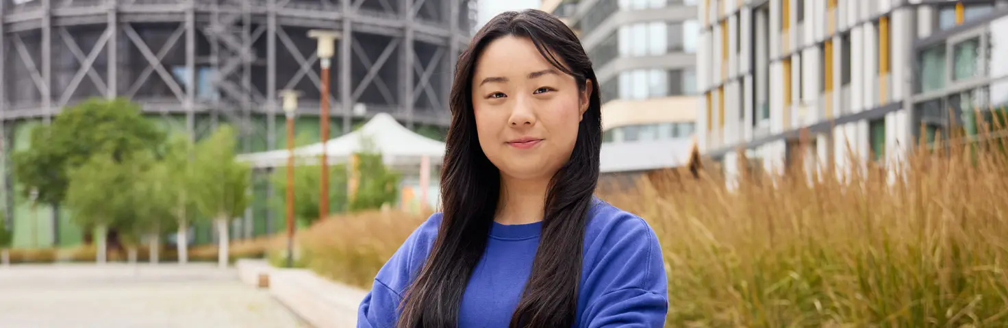 Auszubildende im blauen Oberteil steht mit verschränkten Armen vor dem Hauptsitz der GASAG-Gruppe in Berlin Schöneberg.