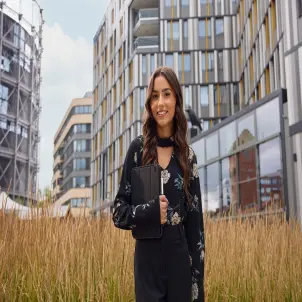 Eine junge Frau steht vor dem GASAG Gebäude, hält ein Pad im Arm und lächelt