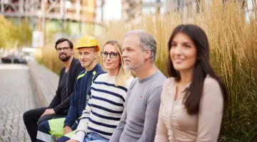 Fünf GASAG-Mitarbeiter sitzen auf dem EUREF-Campus vor dem GASAG-Gebäude