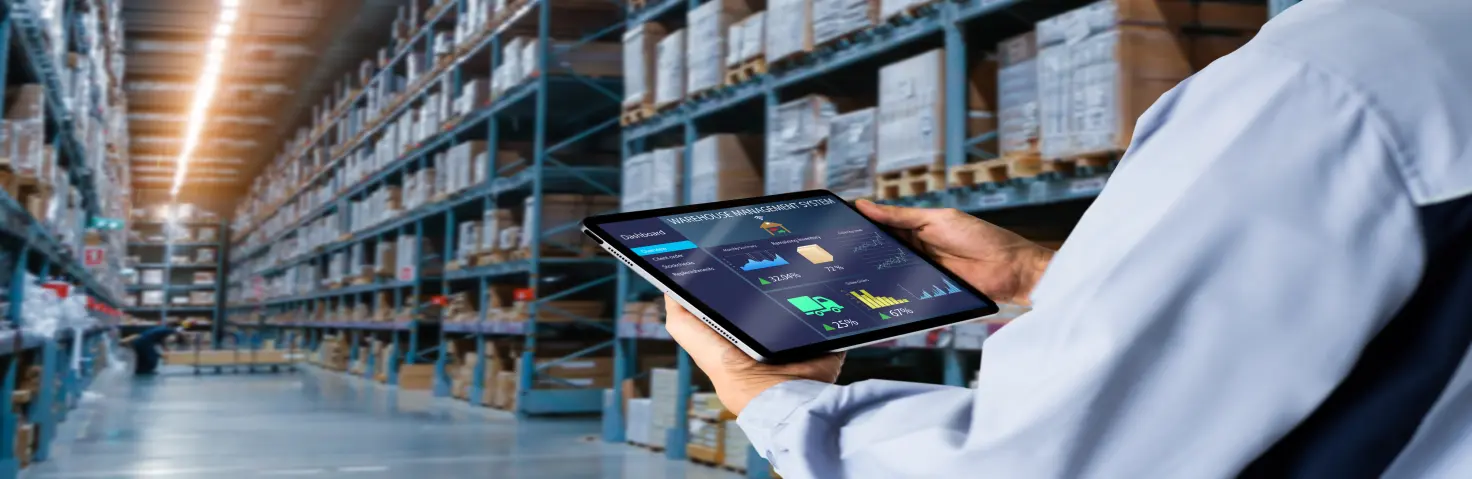 Mann steht in einer Lagerhalle und mit einem Tablet in der Hand