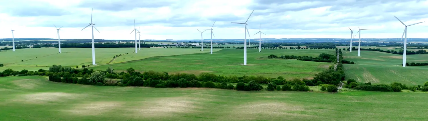 Grüne Felder mit Windrädern und bewölktem Himmel