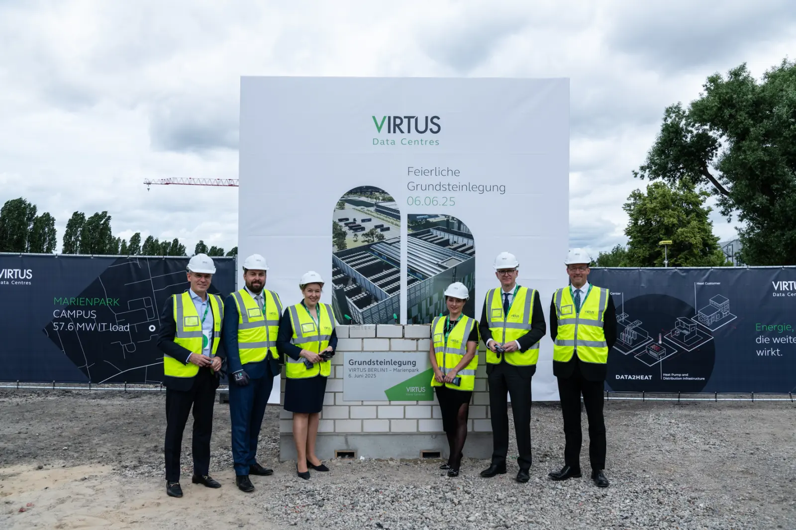 Sechs Personen stehen bei der Grundsteinlegung von Virtus auf der Baustelle