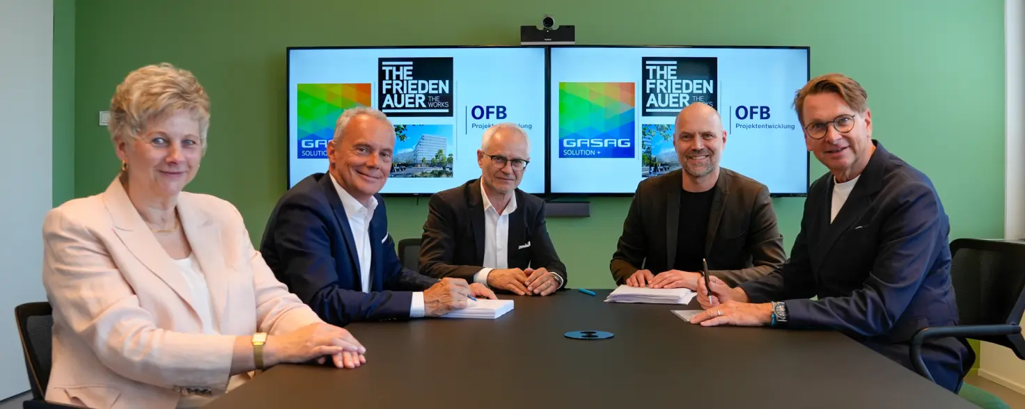 Fünf Projektbeteiligt an einem Konferenztisch unterschreiben Vertrag für Projekt „The Friedenauer“.