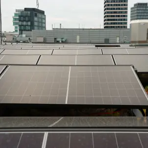 Photovoltaikanlage auf einem Gebäudedach in urbaner Umgebung mit Bürogebäuden im Hintergrund