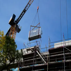 Kran befördert eine große Wärmepumpe auf ein Hausdach