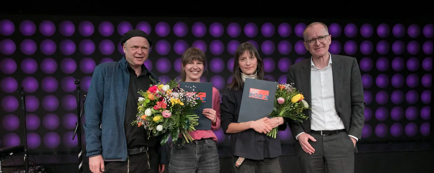 Zwei Männer flankieren zwei Frauen die Preise und Blumensträuße in den Händen halten