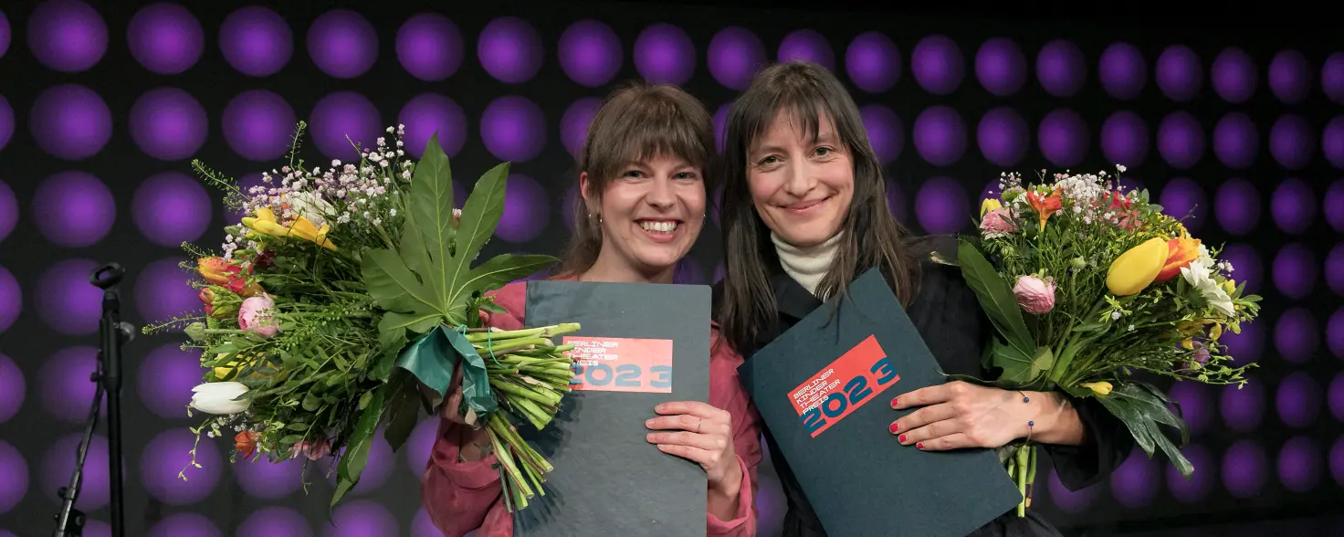 Zwei Frauen mit Preisen und Blumensträußen in der Hand