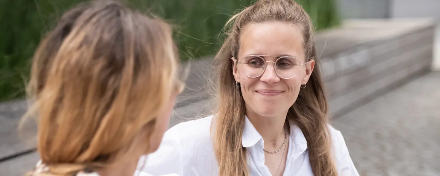 Zwei Frauen sitzen auf einer bunten Bank und unterhalten sich