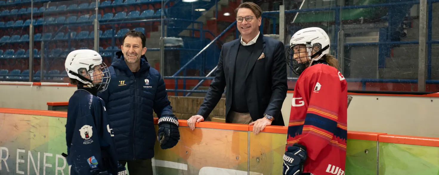 Matthias Trunk, Vorstandsmitglied von GASAG, und Sven Felski von den Eisbären Berlin unterhalten sich mit Eishockey-Spielerinnen und Spielern.