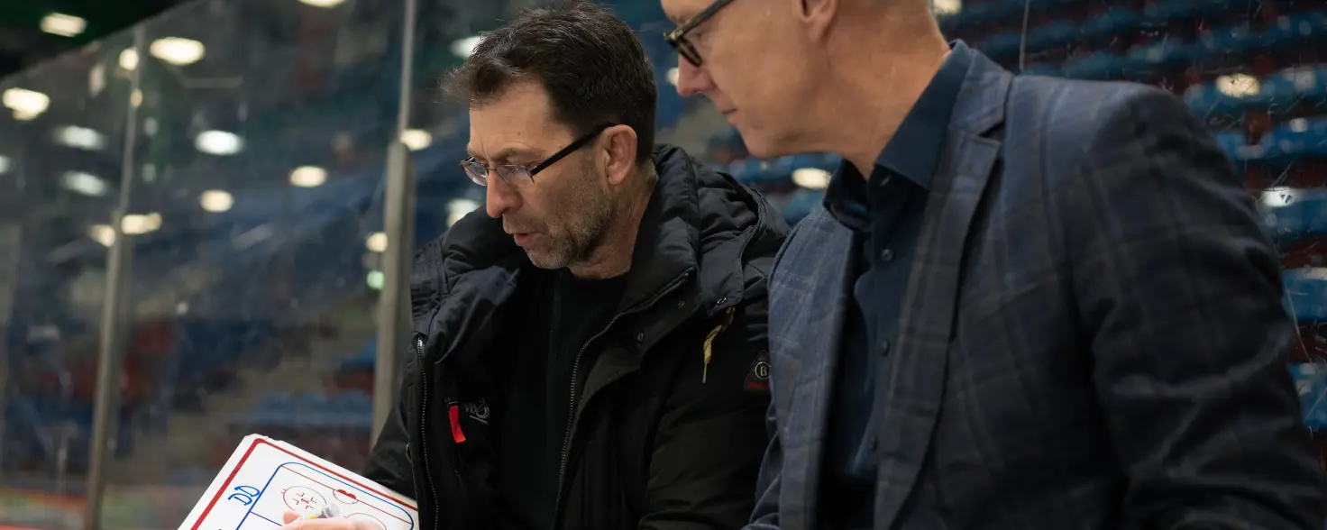 Stefan Hadré von GASAG und Sven Felski von den Eisbären Berlin besprechen eine Strategie und skizzieren Ihr Vorgehen auf einem Blatt Papier.