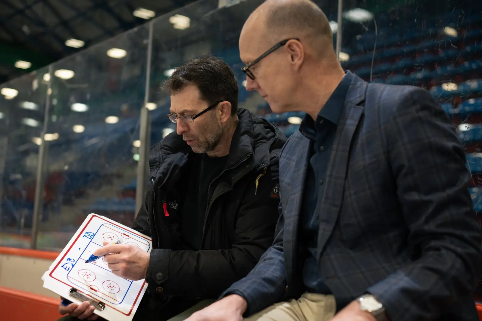 Stefan Hadré von GASAG und Sven Felski von den Eisbären Berlin besprechen eine Strategie und skizzieren Ihr Vorgehen auf einem Blatt Papier.