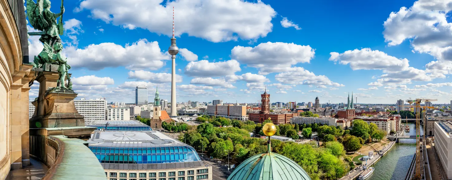 Blick von der Kuppel des Berliner Doms über die Skyline von Berlin-Mitte an einem sonnigen Tag mit blauem Himmel und weißen Wolken.