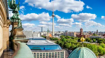 Blick von der Kuppel des Berliner Doms über die Skyline von Berlin-Mitte an einem sonnigen Tag mit blauem Himmel und weißen Wolken.