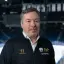 Porträtfoto: Thomas Bothstede, Geschäftsführer der EHC Eisbären Berlin, trägt eine dunkelblaue Trainingsjacke und ein weißes Hemd darunter.