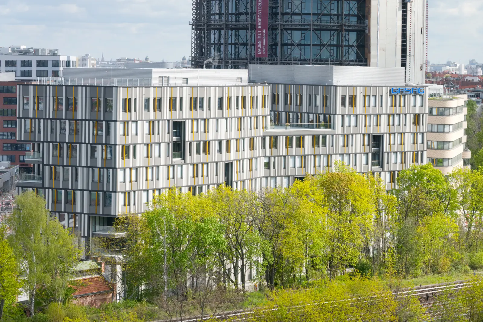 Der GASAG-Hauptsitz in Berlin-Schöneberg mit grünen Bäumen im Vordergrund.