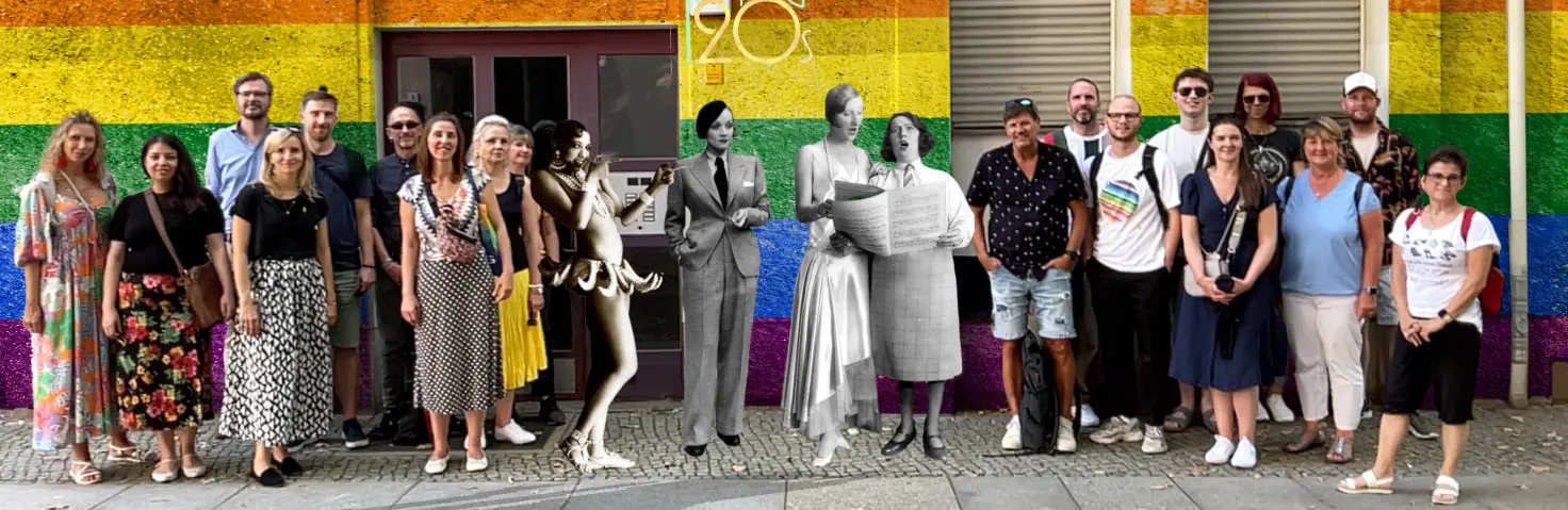 Teilnehmende an der queeren Stadtführung der GASAG-Gruppe vor einer Wand in Regenbogenfarben.